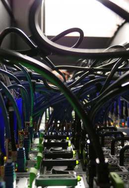 Looking through an archway formed by tightly packed cables connected to flashing computer servers.