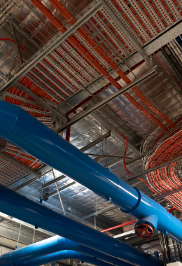 The ceiling of an industrial room, with neatly lined up orange electrical cables travelling in careful paths.