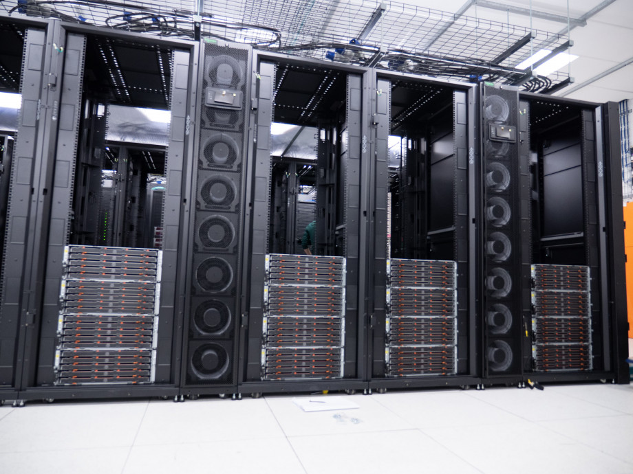 Four empty black server racks are one-third filled from the bottom up with sets of four stacked orange and black draws.