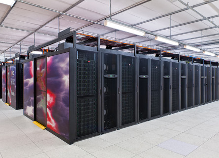Looking at the corner of the supercomputer with rows of servers extending both ways to the edge of the picture.