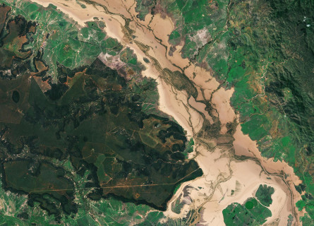 A satellite image of a brown flooded river amongst vivid green bushland in Queensland in 2017.