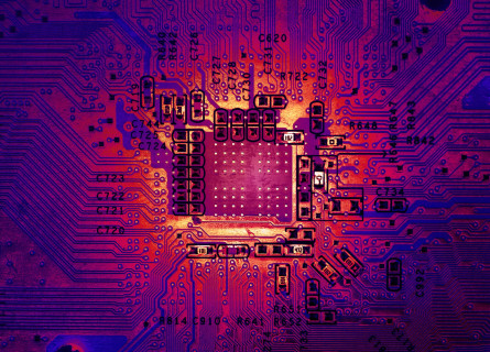 Close up look at a shiny computer motherboard coloured in shades of red and purple, with a golden glow coming off it.
