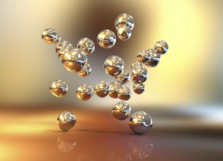 Image showing dozens of balls, representing nanomaterials, floating in the air, reflecting off each other with a golden hue all around them.