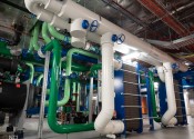 A complex series of green, blue and white pipes connected to tall blue and grey machines.