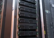 A tall rack comprising around a dozen horizontal black computer servers stacked on top of each other.