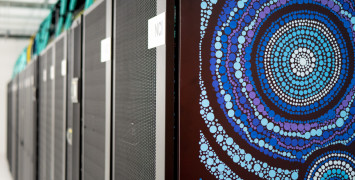 Close-up view of the Gadi artwork with the long row of supercomputer servers visible in the background.