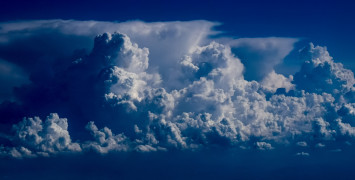 A blue-tinged picture of a large wide storm cloud in the distance.